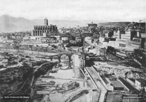 Vista general de Manresa al tombant de segle. L'arbreda del camí de Sant Pau, la fàbrica del Pont Vell i la Cova a la riba dreta del riu; a la riba esquerra, les diverses vies del ferrocarril del Nord. La basílica de la Seu al fons, encimbellada damunt del turó del Puigcardener.
Procedència: Arxiu Comarcal del Bages