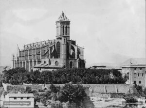 La Seu i els jardins que l'envolten. A la dreta, l'edifici dels jutjats, que també des del 1882 encabí provisionalment la sala de l'Audiència del Criminal. La fotografia degué ser presa l'any 1917: el nou baptisteri ja hi és adossat, mentre que l'agulla piramidal del campanar és a punt de ser aixecada. Els jardins del parc foren condicionats l'any 1887.
Procedència: Arxiu Jaume Pons i Agulló
