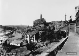 La ciutat vista des de la baixada de la Cova de Sant Ignasi. Imatge obtinguda, molt probablement, al començament dels anys vint del segle passat. Notables millores urbanístiques i arquitectòniques separen aquesta perpectiva de l'anterior: les transformacions de la Seu, l'embelliment del seu parc o antic fossar; l'accés directe a la Casa d'Exercicis (encara per construir en aquesta fotografia); fins i tot, la casa que apareix al peu del camí de la Cova ha sofert obres de reforma i, finalment, cal remarcar que l'electricitat ha arribat també al tantes vegades abandonat districte cinquè (que comprenia el barri de la Cova, torrent de Sant Ignasi, les Escodines i Santa Clara enllà).
Procedència: Arxiu Comarcal del Bages