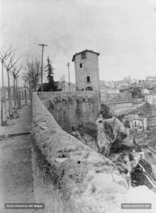La Casa de les Ànimes, en un extrem del parc de la Seu, al tombant de segle XX. Al fons i a la dreta, la Cova, la casa de la Culla i el convent de Santa Clara. La Casa de les Ànimes, bastida l'any 1760, era una dependència de l'antic fossar de la Seu. A les 7 de la tarda del 3 de setembre de 1906 va ser objecte d'un simulacre d'extinció de foc desenvolupat pels bombers. El Diario de Avisos ressenyava aquest esdeveniment així: «El fuego que se inició en la parte alta de la casa, fue propagándose a todas las dependencias de la misma, produciendo un efecto imponente las llamas que se escapaban por el tejado, ventanas y puertas de entrada, en tanto los bomberos simulaban las operaciones de salvamento y extinción, sumisos a la voz de las cornetas y pitos, con una precisión digna de toda suerte de elogios. Hiciéronse grandes refuerzos para derrumbar de una vez toda la casa, pero no pudo lograrse más que parcialmente, gracias a la consistencia de sus columnas interiores» .
Procedència: Col·lecció Andreu Argelich