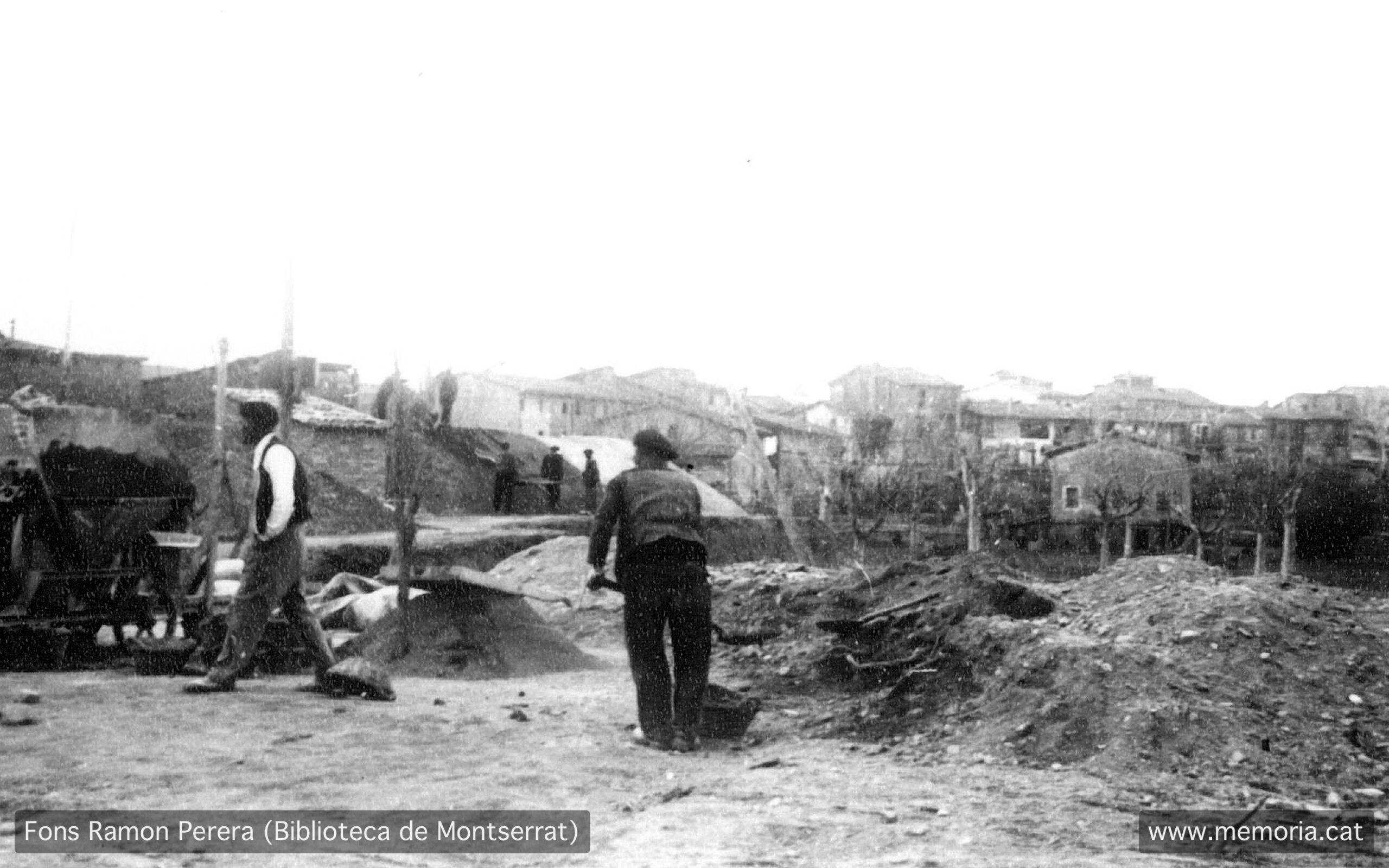 Vic. 24 març 1938. Obres de construcció d’un refugi als afores de Vic. Per la data de la fotografia i la forma del talús de sobre el refugi, probablement sigui el refugi antiaeri del darrera del carrer del Remei, pel cantó de la carretera de Barcelona. En la imatge es poden veure el que sembla que són els plataners del Prat de la Riera i al fons els darreres de les cases del carrer de Sant Pere.