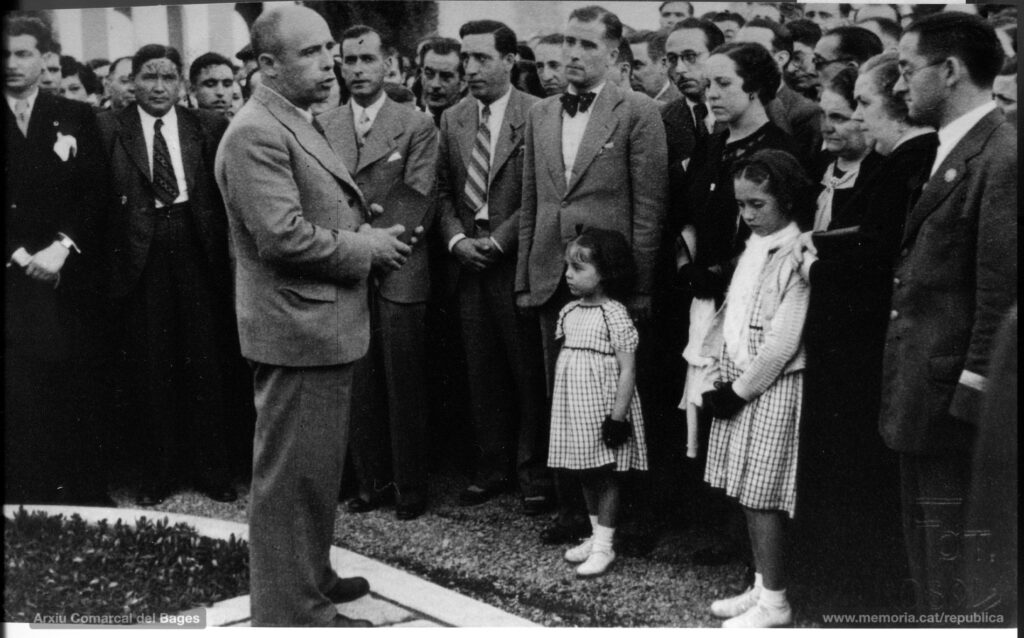 12/7/1936: acte del trasllat de les despulles de Joan Selves i Carner al panteó erigit per l’Ajuntament al cementiri de Manresa. L’alcalde Francesc Marcet s’adreça als assistents. Al seu davant les filles de Joan Selves, la Carme i la Maria.